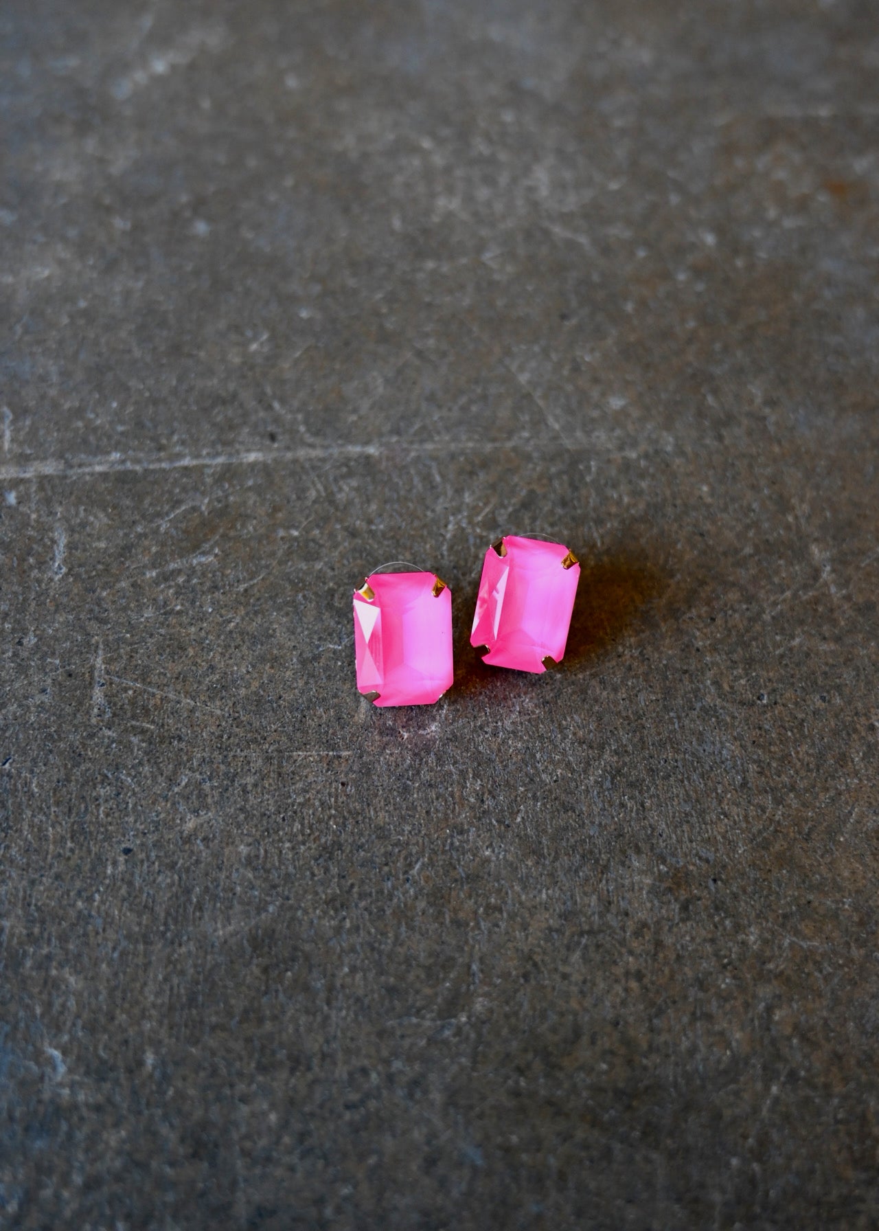 Emerald cut neon pink earrings on a dark background