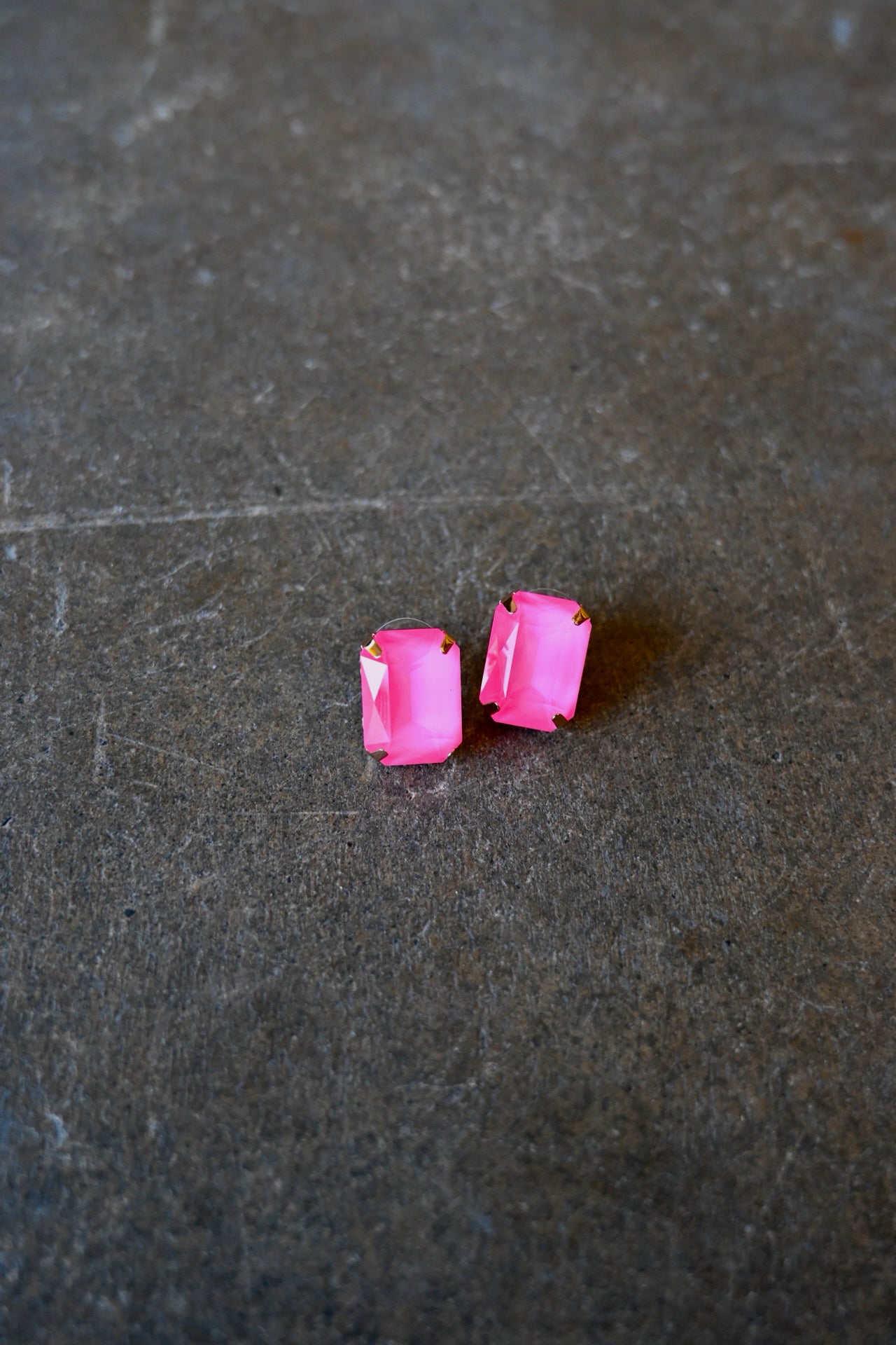 Emerald cut neon pink earrings on a dark background