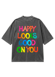 Gray graphic short sleeve shirt with colorful text 'Happy Looks Good On You' on a white background, flat lay frontal view