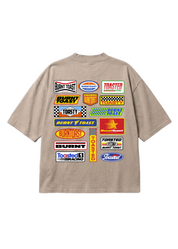 A beige short-sleeve t-shirt shown from the back, featuring a large graphic print of various racing decals and logos including 'Burnt Toast', 'Toasted Race Racing', and 'Ford'