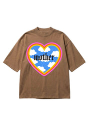 A brown short-sleeve t-shirt with a large heart-shaped graphic on the chest. The graphic features a blue sky with white clouds, a yellow and pink rainbow border, and the word 'mother' written in a black gothic font