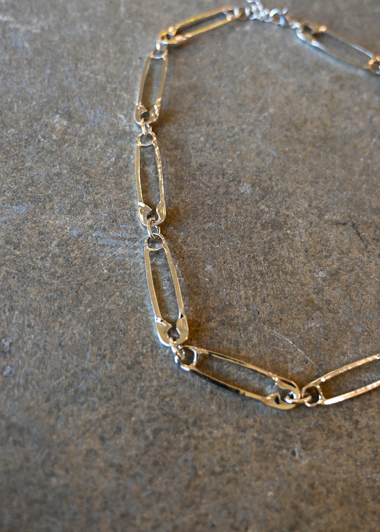 Close up of a silver necklace made of safety pins on a dark background