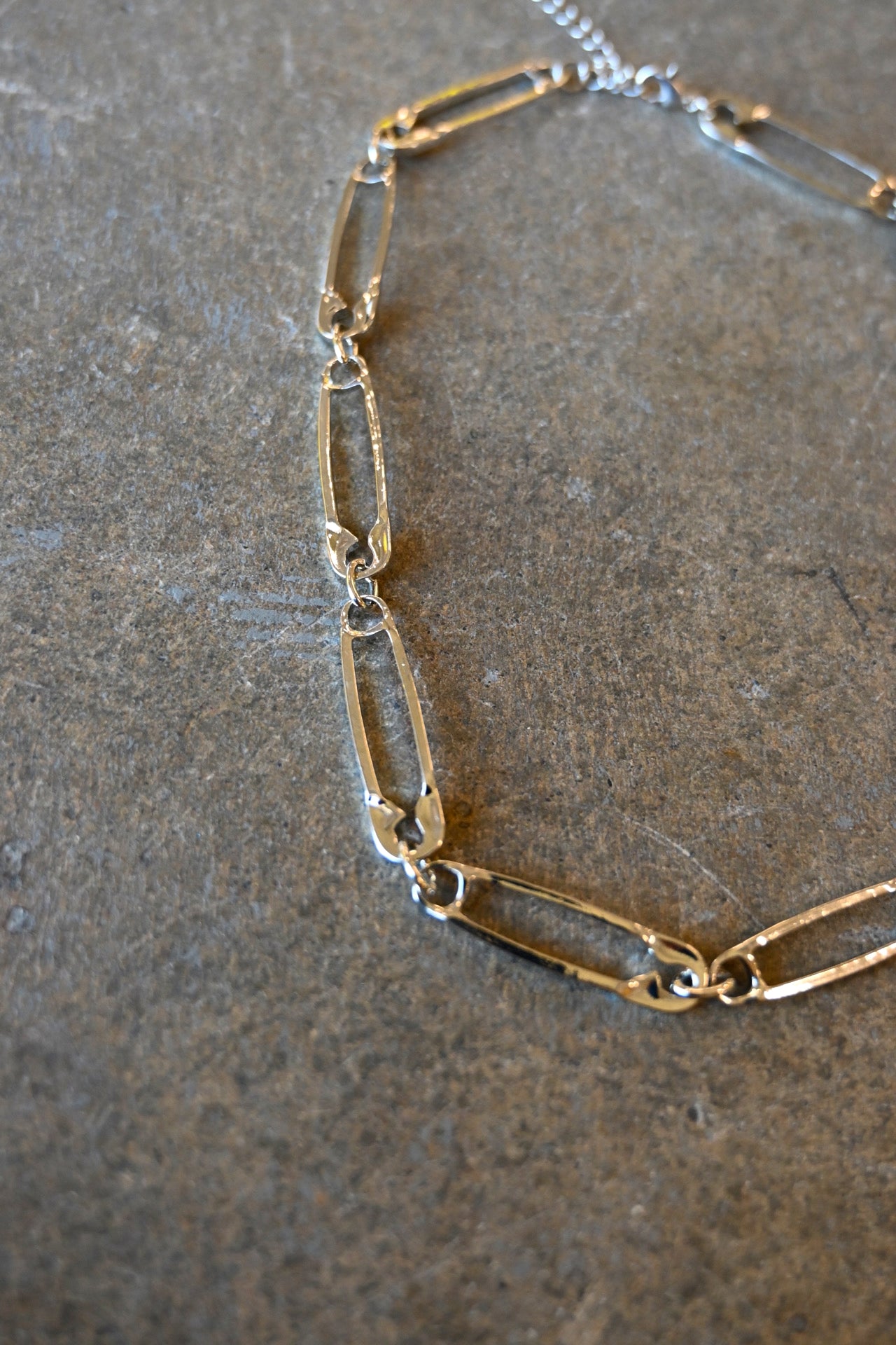 Close up of a silver necklace made of safety pins on a dark background