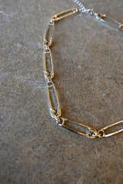 Close up of a silver necklace made of safety pins on a dark background
