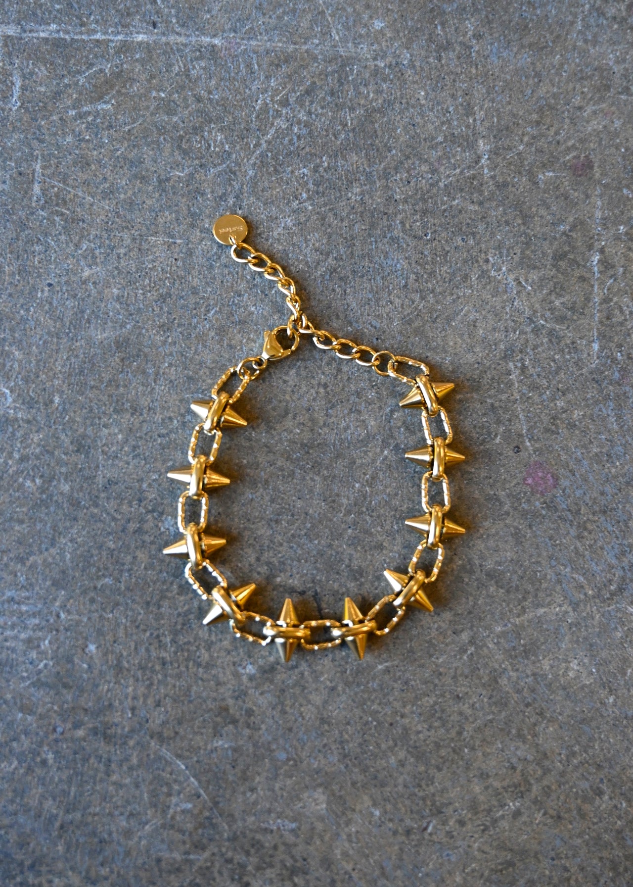 A gold bracelet with spikes on a dark background