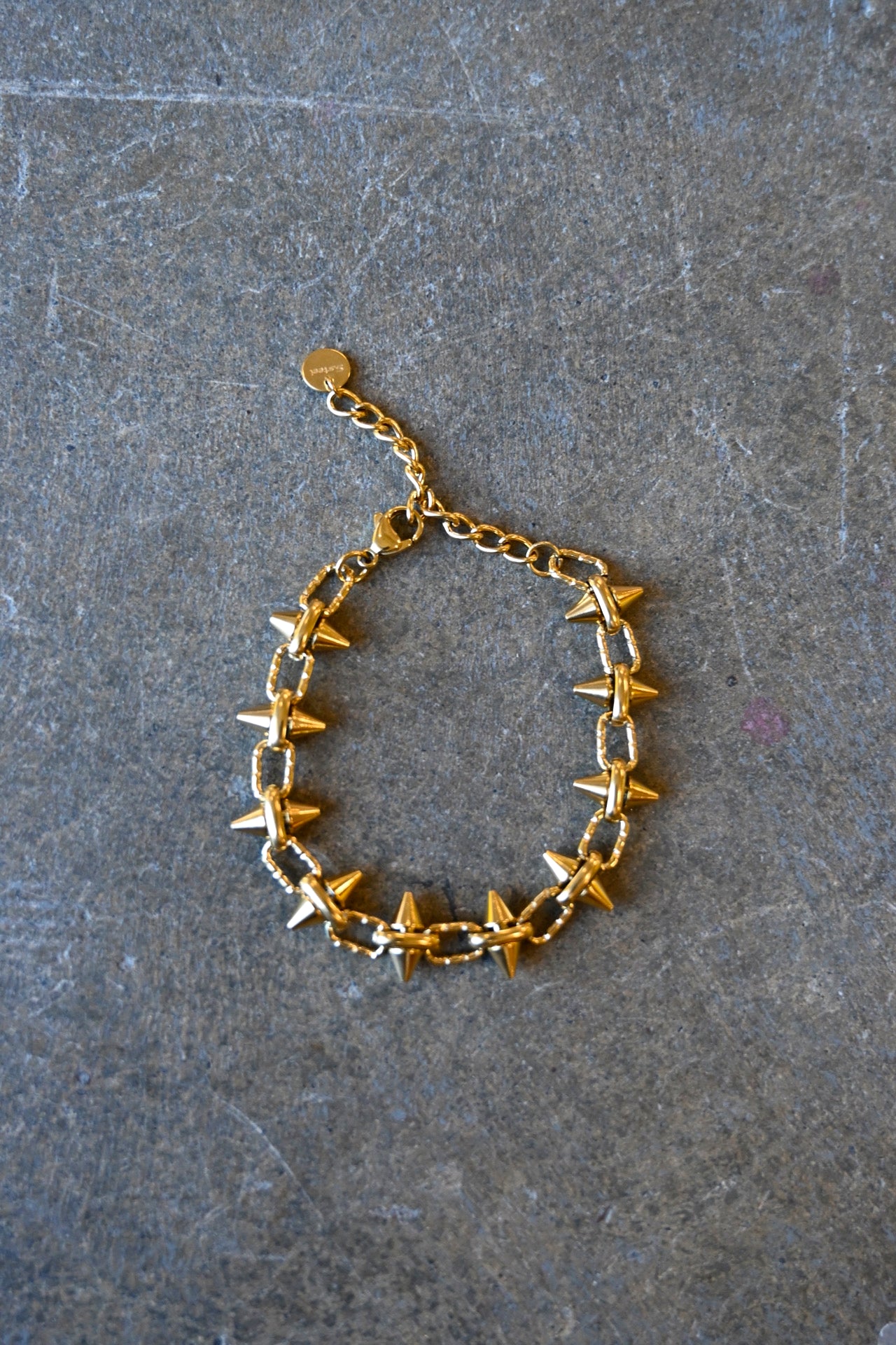 A gold bracelet with spikes on a dark background
