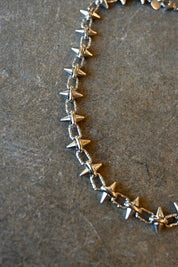 Close up of a silver necklace with spike studs around it on a dark background