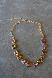 A gold bracelet made of multi-color square gems on a dark background