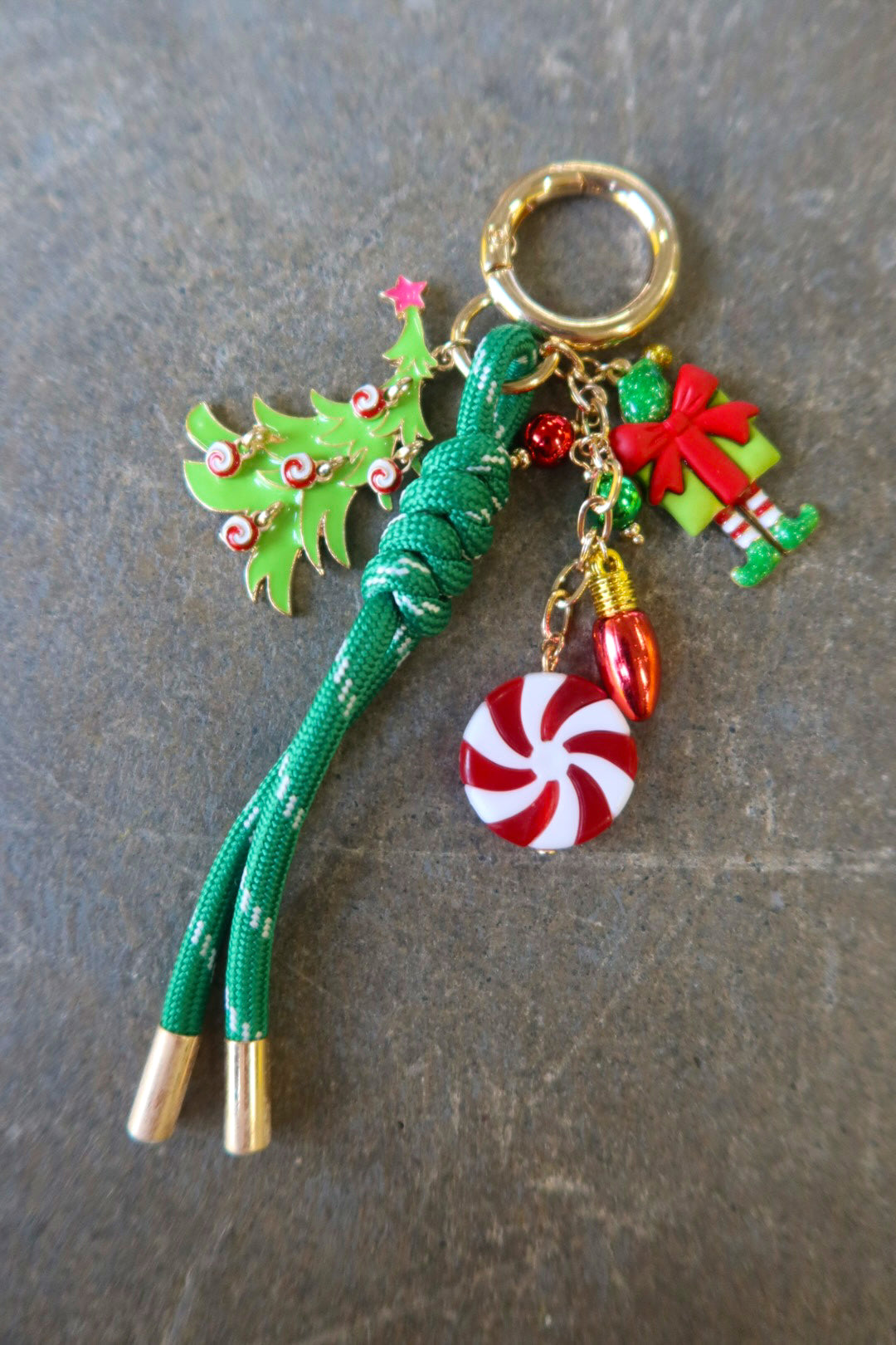 A gold ring bag charm with different Christmas charms on a dark surface
