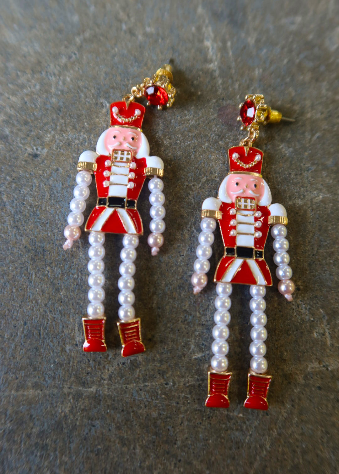 Pair of nutcracker earrings with pearls on a dark surface