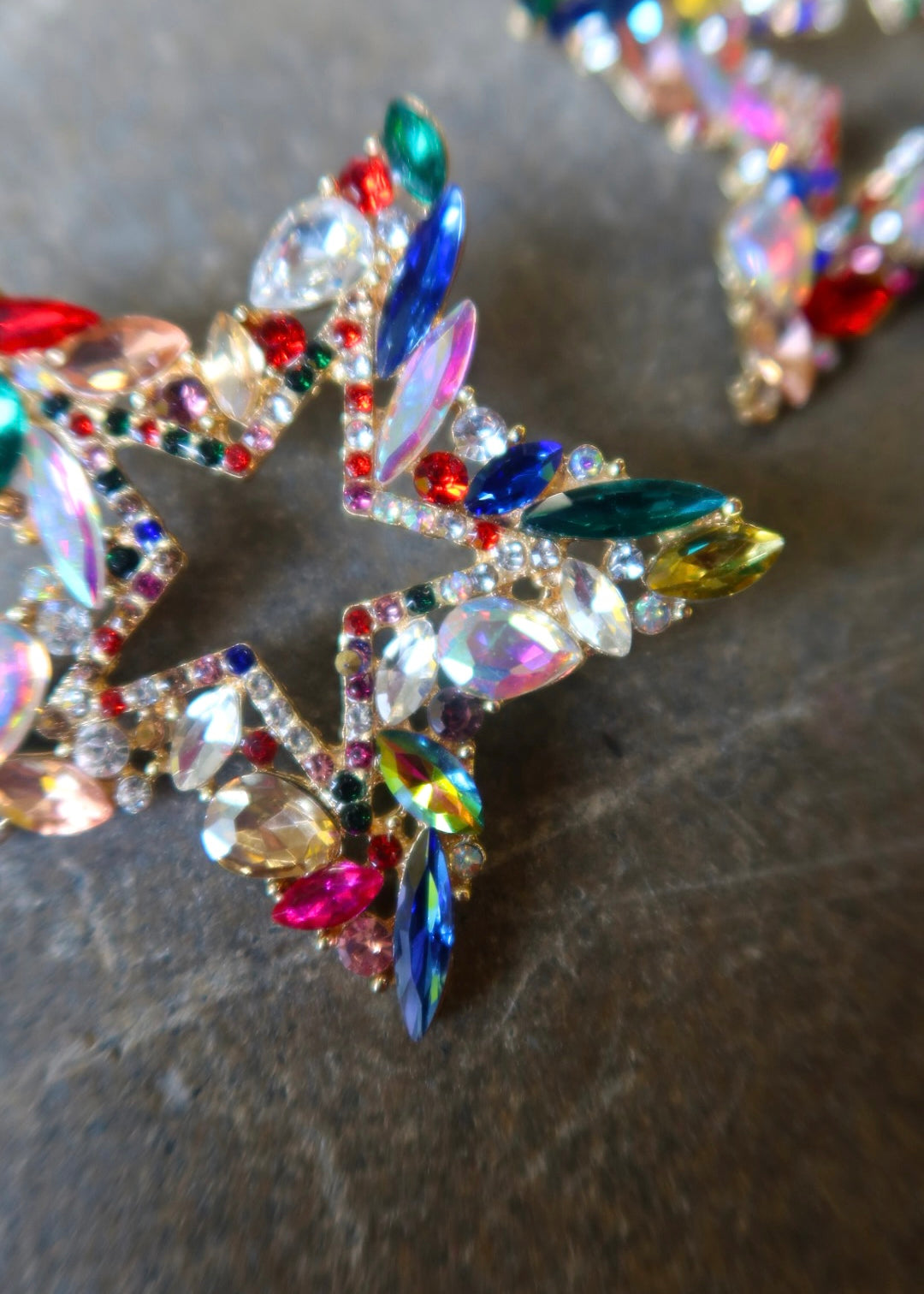 Close up of oversized bedazzled star earrings on a dark surface