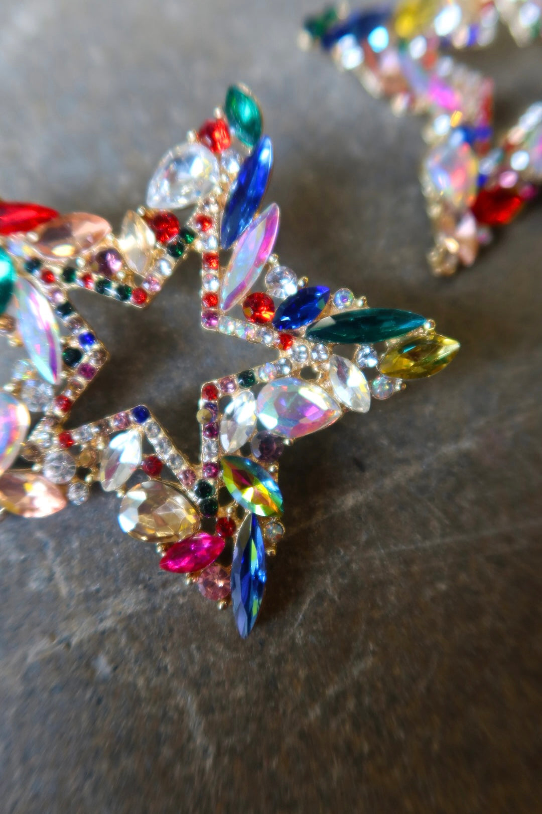 Close up of oversized bedazzled star earrings on a dark surface