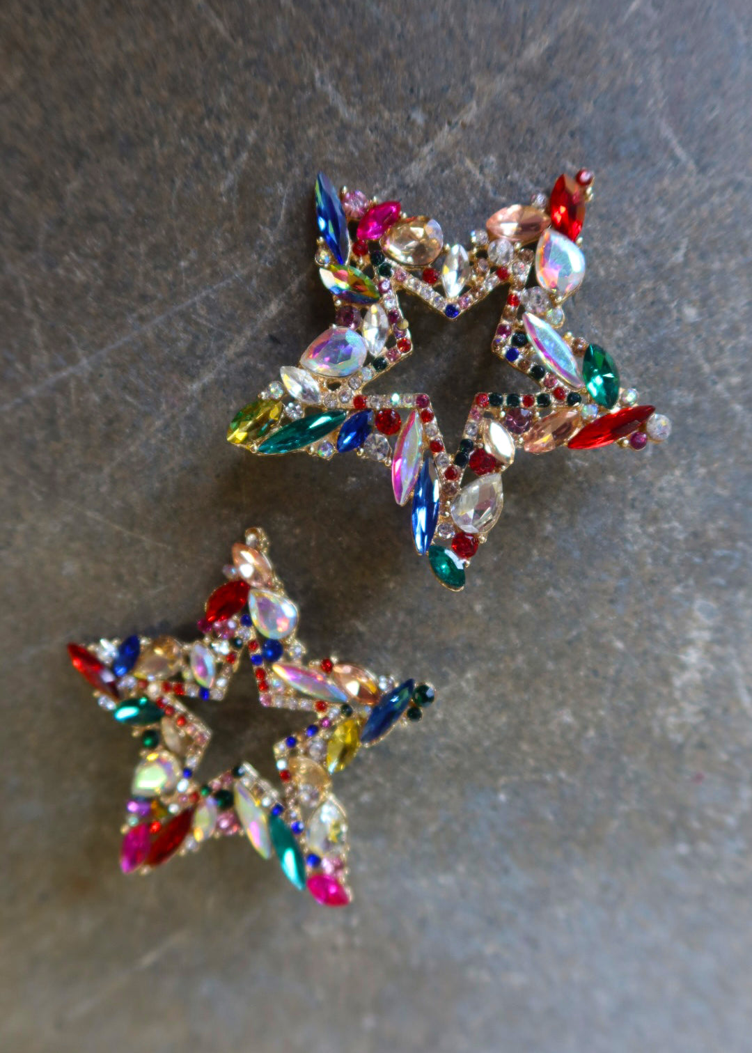 Oversized bedazzled star earrings on a dark surface