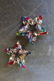 Oversized bedazzled star earrings on a dark surface