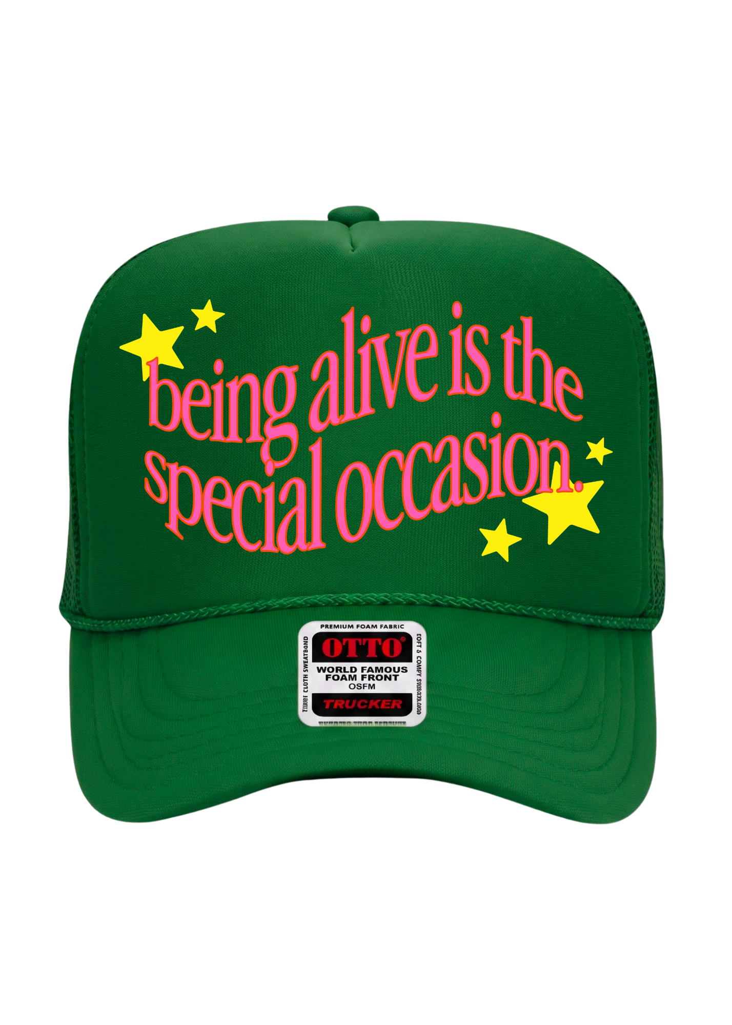 A green trucker-style cap with pink text reading 'being alive is the special occasion' and yellow stars, shown on a plain white background. A front patch reads OTTO
