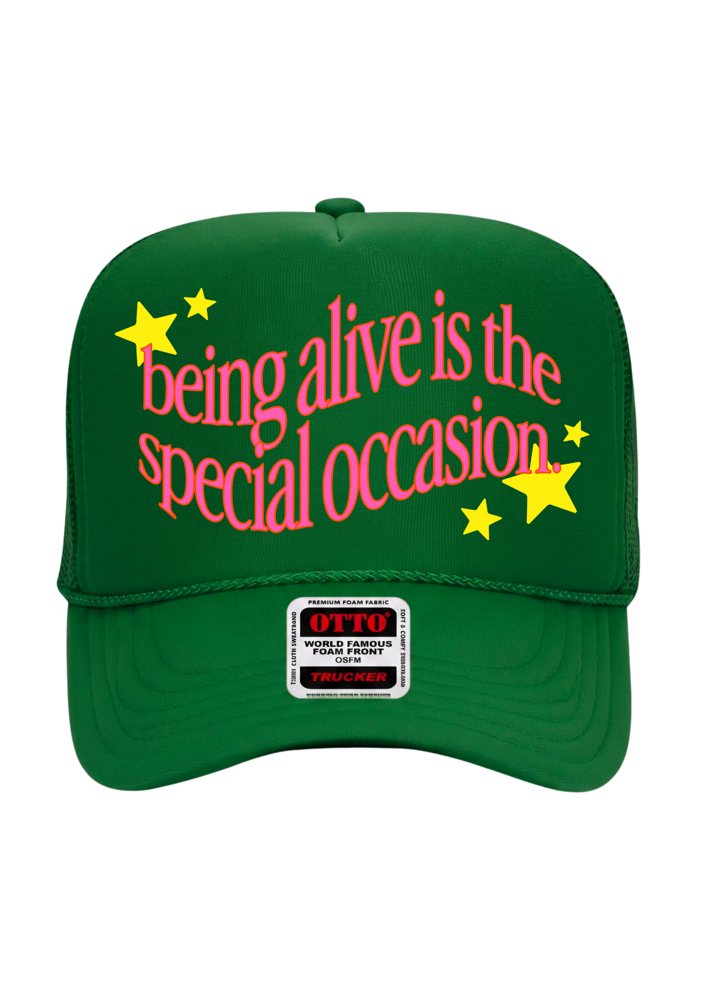 A green trucker-style cap with pink text reading 'being alive is the special occasion' and yellow stars, shown on a plain white background. A front patch reads OTTO