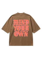 Back of a brown short sleeve shirt with the text MIND YOUR OWN in pink on a white background