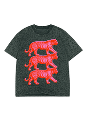 A dark grey short-sleeve t-shirt with an allover tonal leopard print, featuring a large graphic of three stacked, bright neon pink stylized tigers on the front
