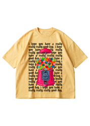 A yellow tee with a graphic of gumball machine and repeating text in the background that reads 'I hope you have a really, really good day' in black on a white background