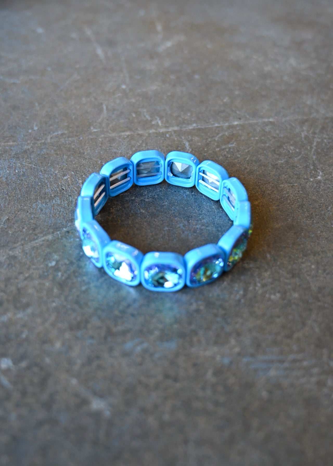 A stretchy bracelet with oval light blue jems on a dark background
