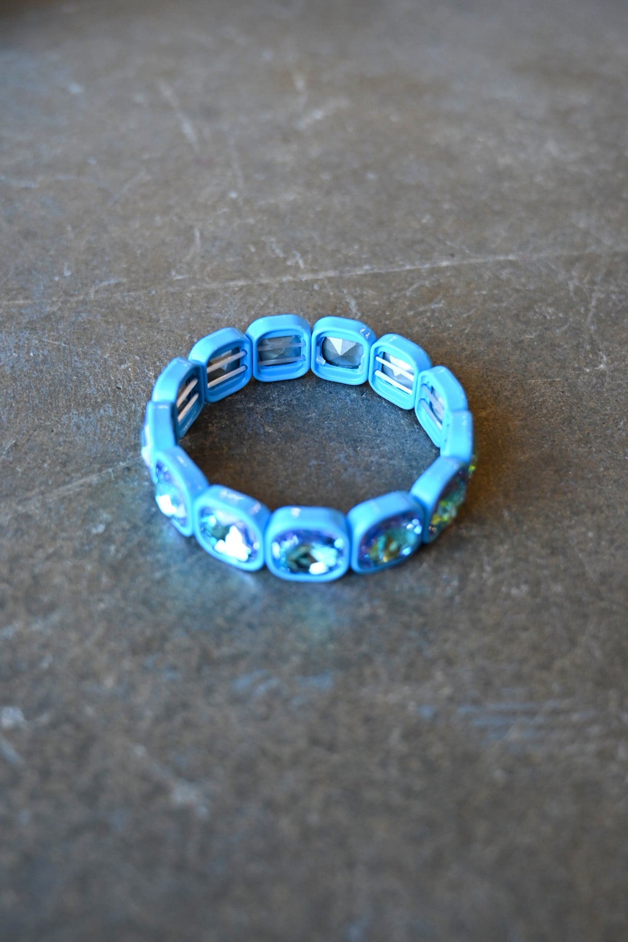 A stretchy bracelet with oval light blue jems on a dark background