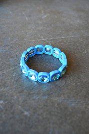 A stretchy bracelet with oval light blue jems on a dark background