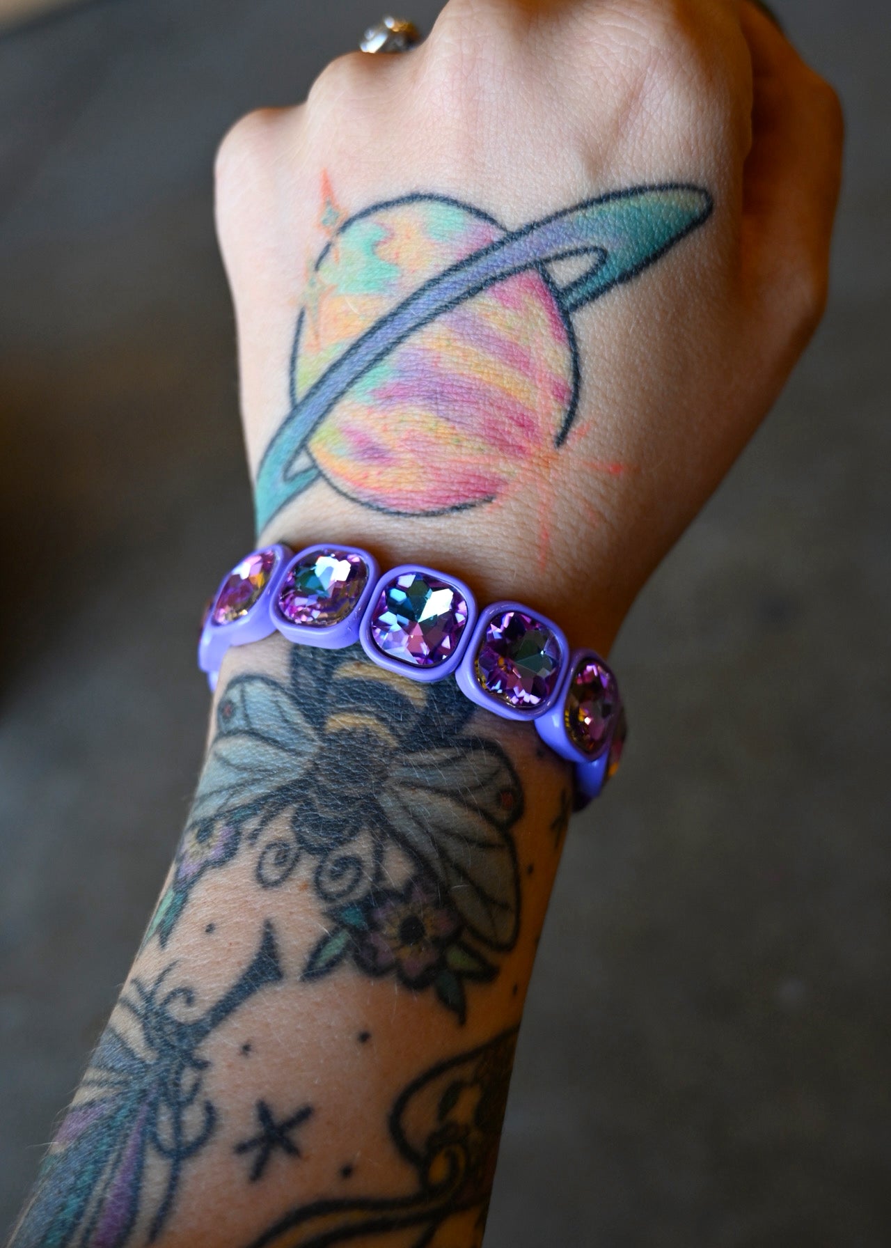 A model wearing a purple gemstone bracelet on a dark background