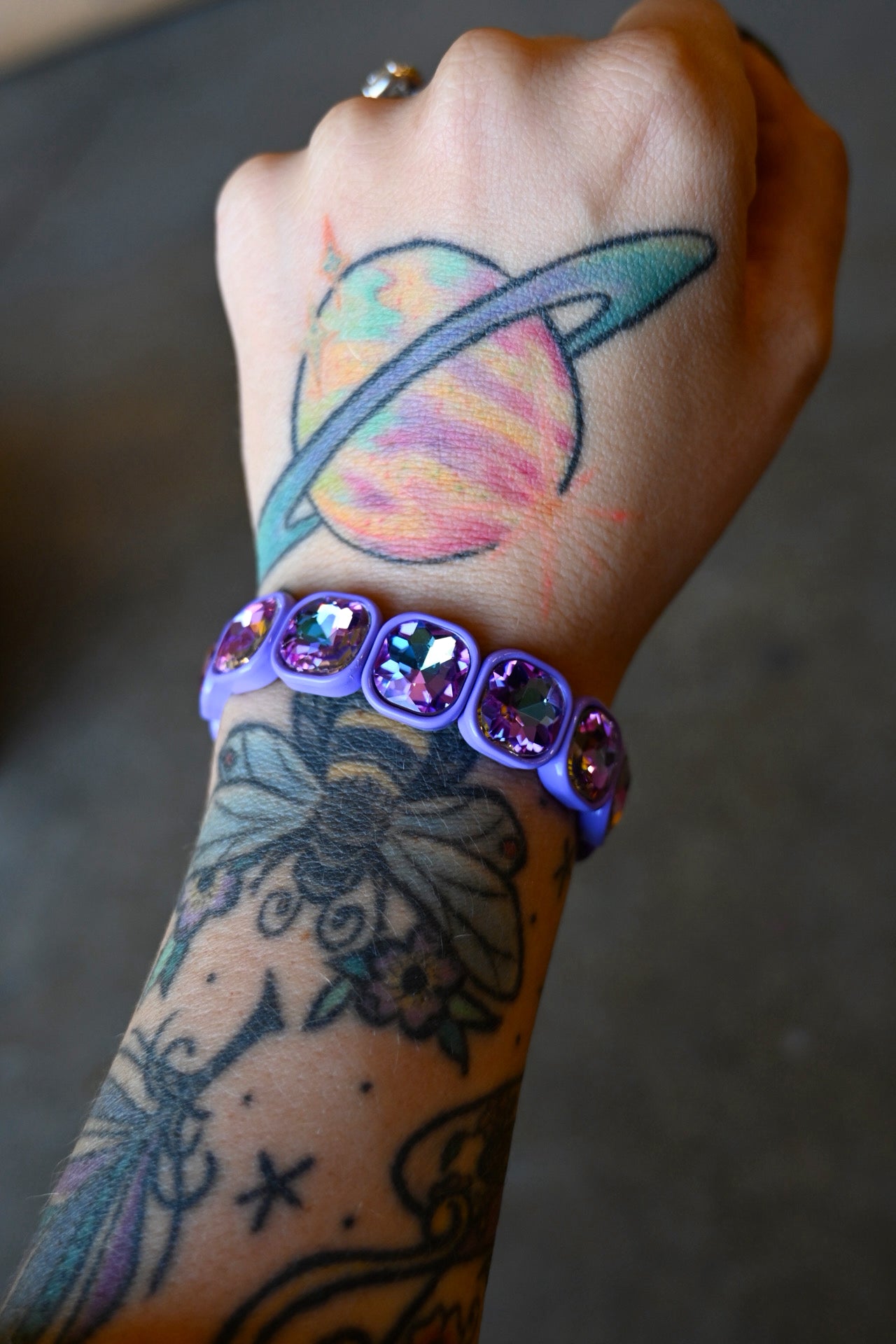 A model wearing a purple gemstone bracelet on a dark background