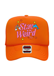 An orange trucker-style cap with a colorful graphic on the front that reads 'Stay Weird' in pink and white, decorated with a rainbow, blue dolphin, yellow stars, and red lips. A white brand patch for 'OTTO World's Famous Trucker' is visible on the brim.