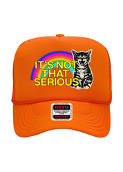 An orange trucker hat with a graphic on the front featuring a rainbow, a black-and-white cat, and the text 'IT'S NOT THAT SERIOUS' in yellow. A sewn-on brand patch on the brim reads 'OTTO WORLD'S FAMOUS TRUCKER'.