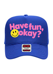 A royal blue trucker hat with pink text reading 'Have fun, okay?' and a yellow smiley face graphic on the front. A visible front patch shows the brand OTTO.