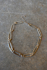 A silver necklace made of safety pins on a dark background